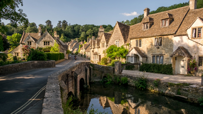 The Cotswolds village view with river bridge and old brick cottages